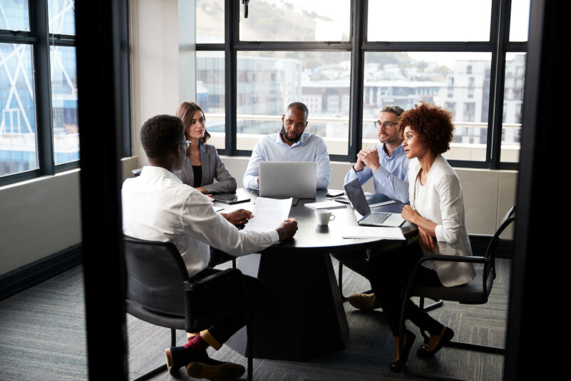 Corporate business colleagues talking in a meeting room, seen from doorway