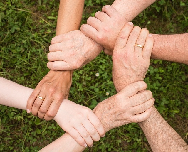 Close-up of hands joined in a circle, representing team alignment, collaboration, and the unity fostered by daily huddles or stand-up meetings